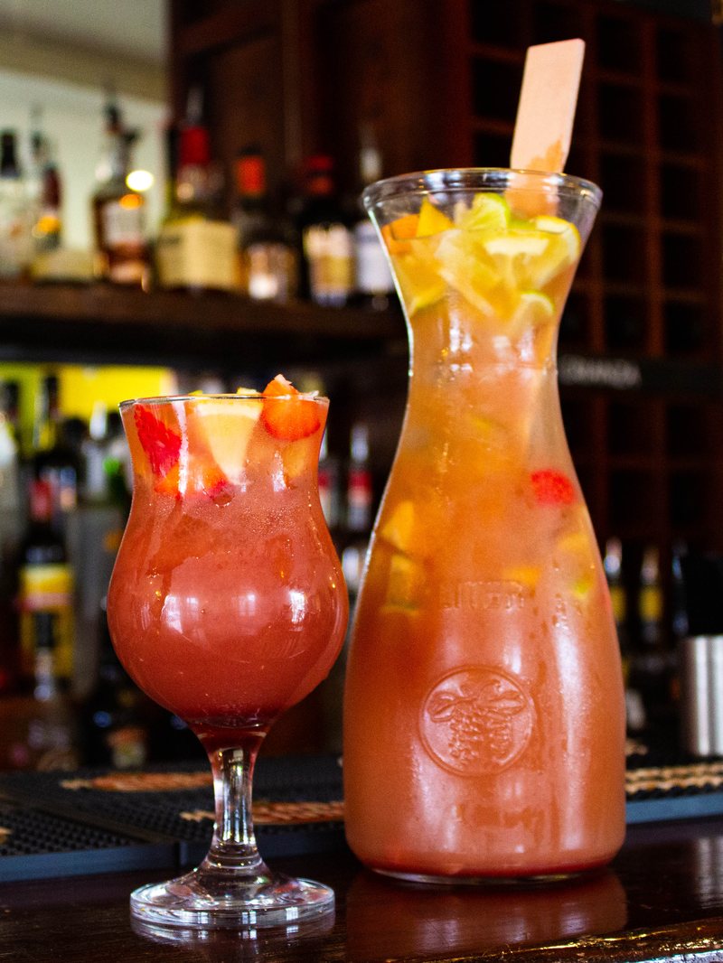 A jug and glass of strawberry rosé sangría on the bar